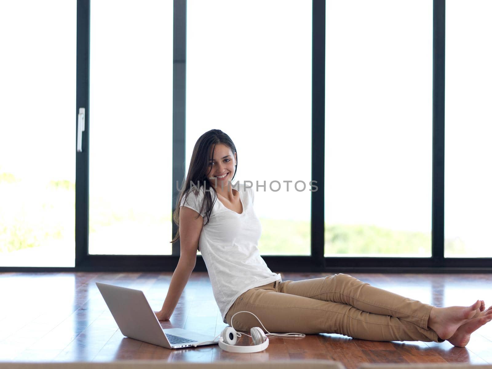 beautiful young woman relax and work on laptop computer modern  home office while listening musin on white headphones