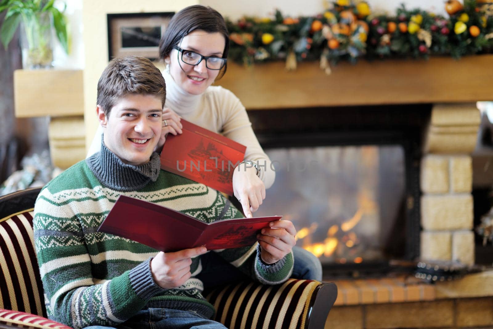 Young romantic couple relax on sofa in front of fireplace at home by dotshock