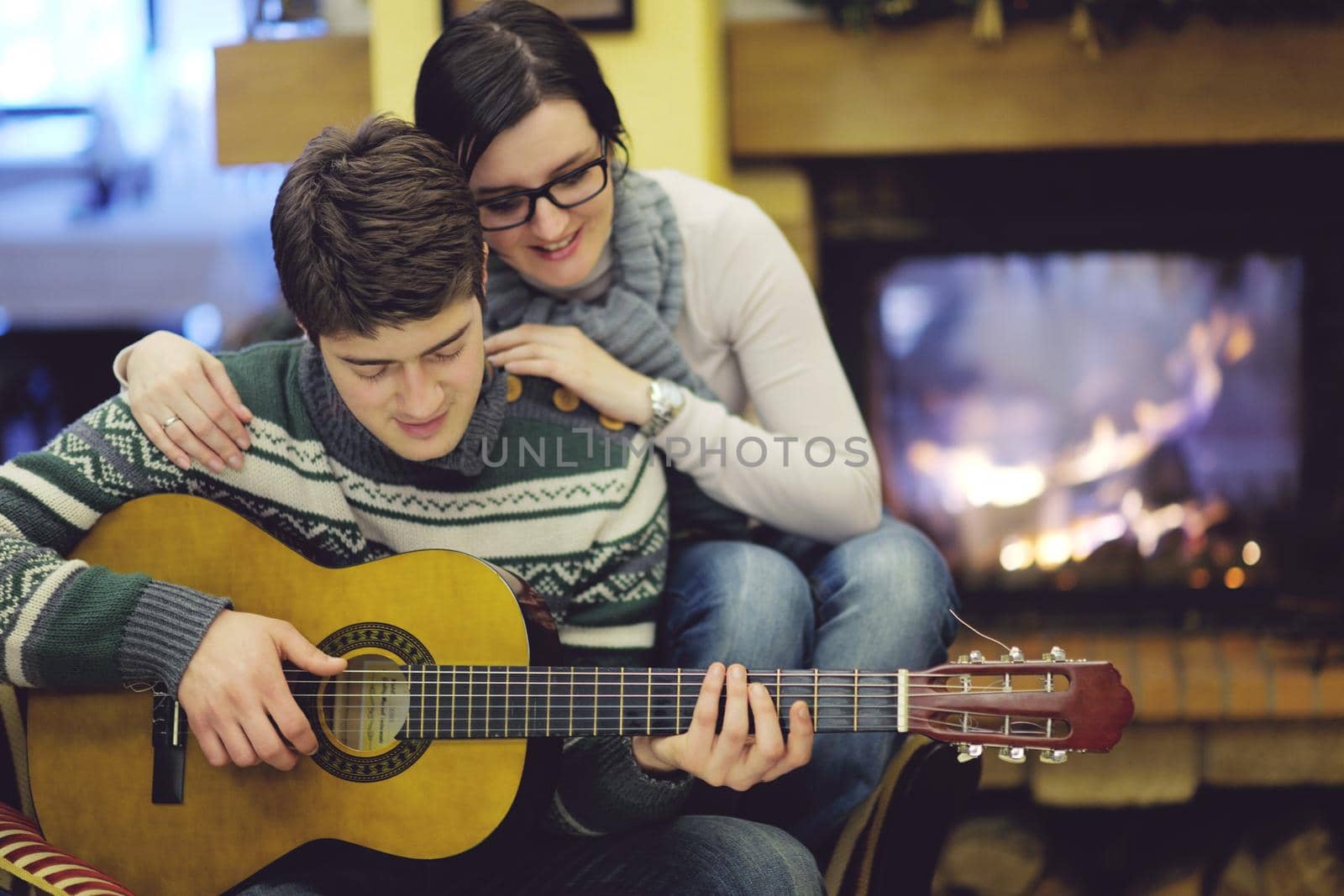 Young romantic couple sitting and relaxing in front of fireplace at home by dotshock