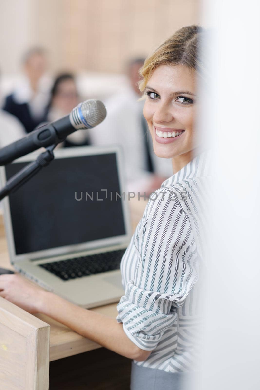 business woman standing with her staff in background at modern bright office conference room