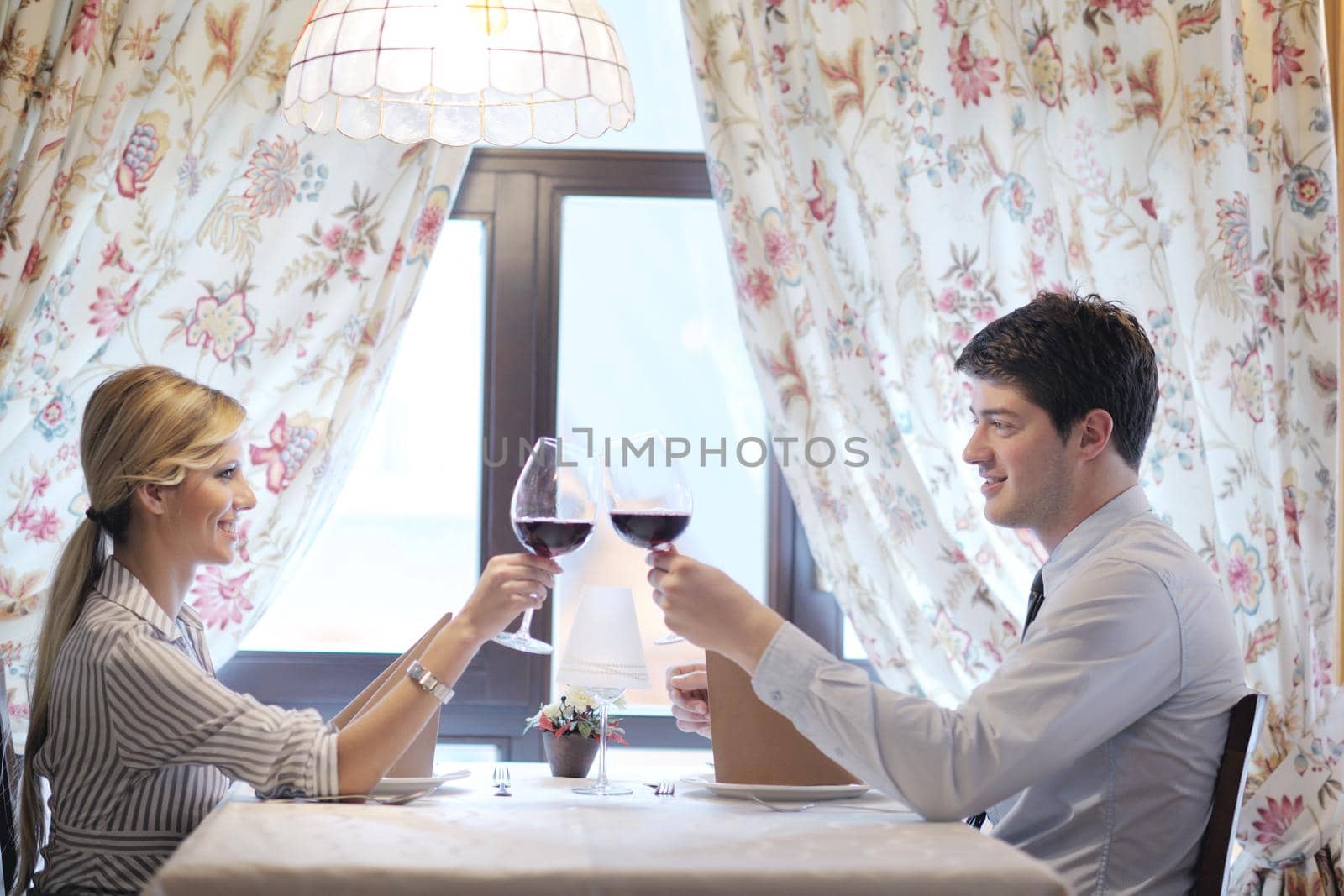 young couple having dinner at a restaurant by dotshock