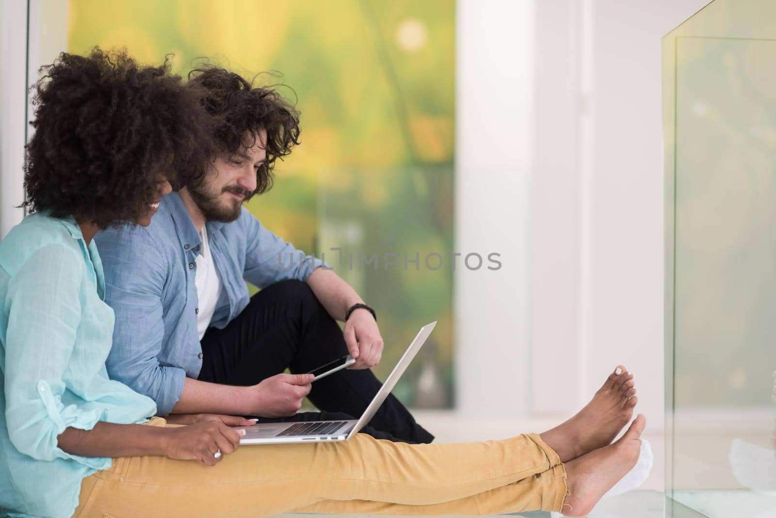 multiethnic couple using a laptop on the floor by dotshock