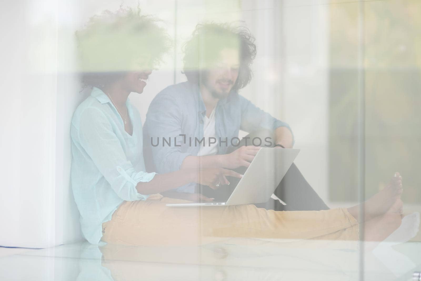 multiethnic couple using a laptop on the floor by dotshock