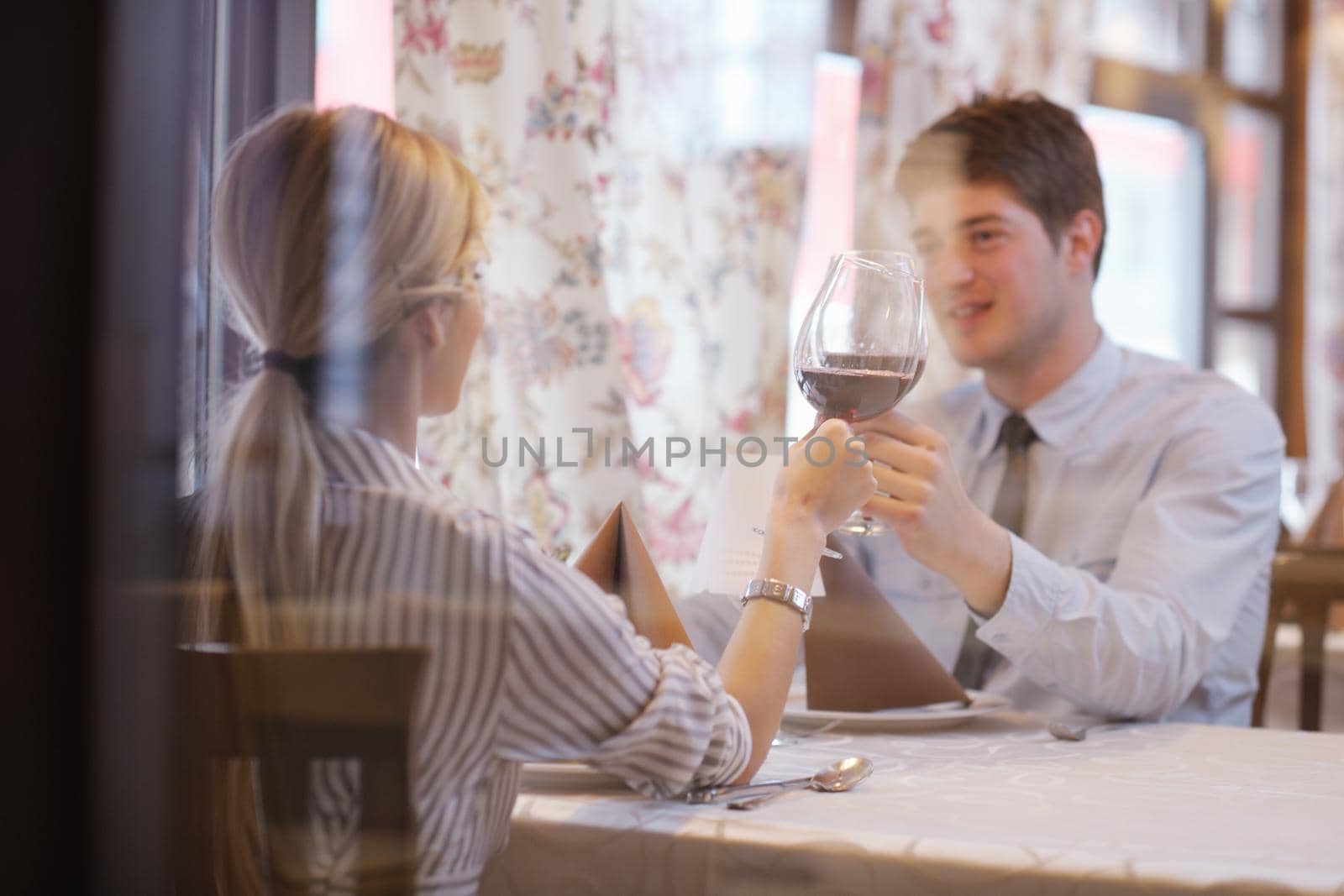 young couple having dinner at a restaurant by dotshock