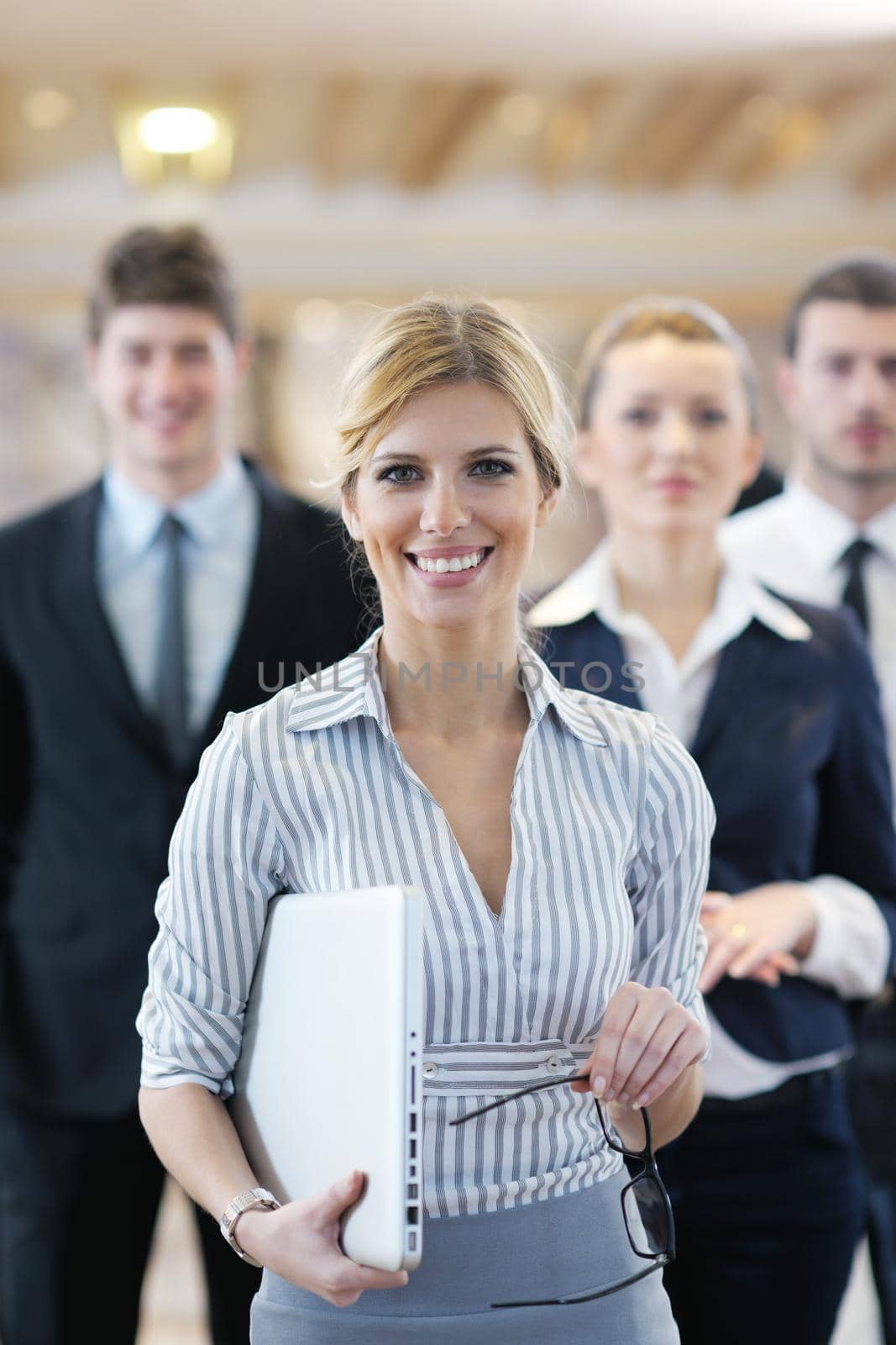business woman standing with her staff in background at modern bright office conference room