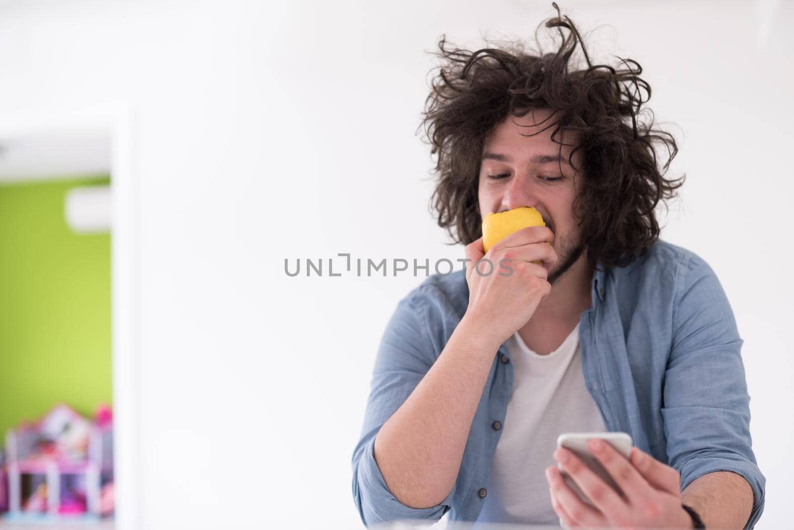 young man eating apple and using a mobile phone  at home by dotshock