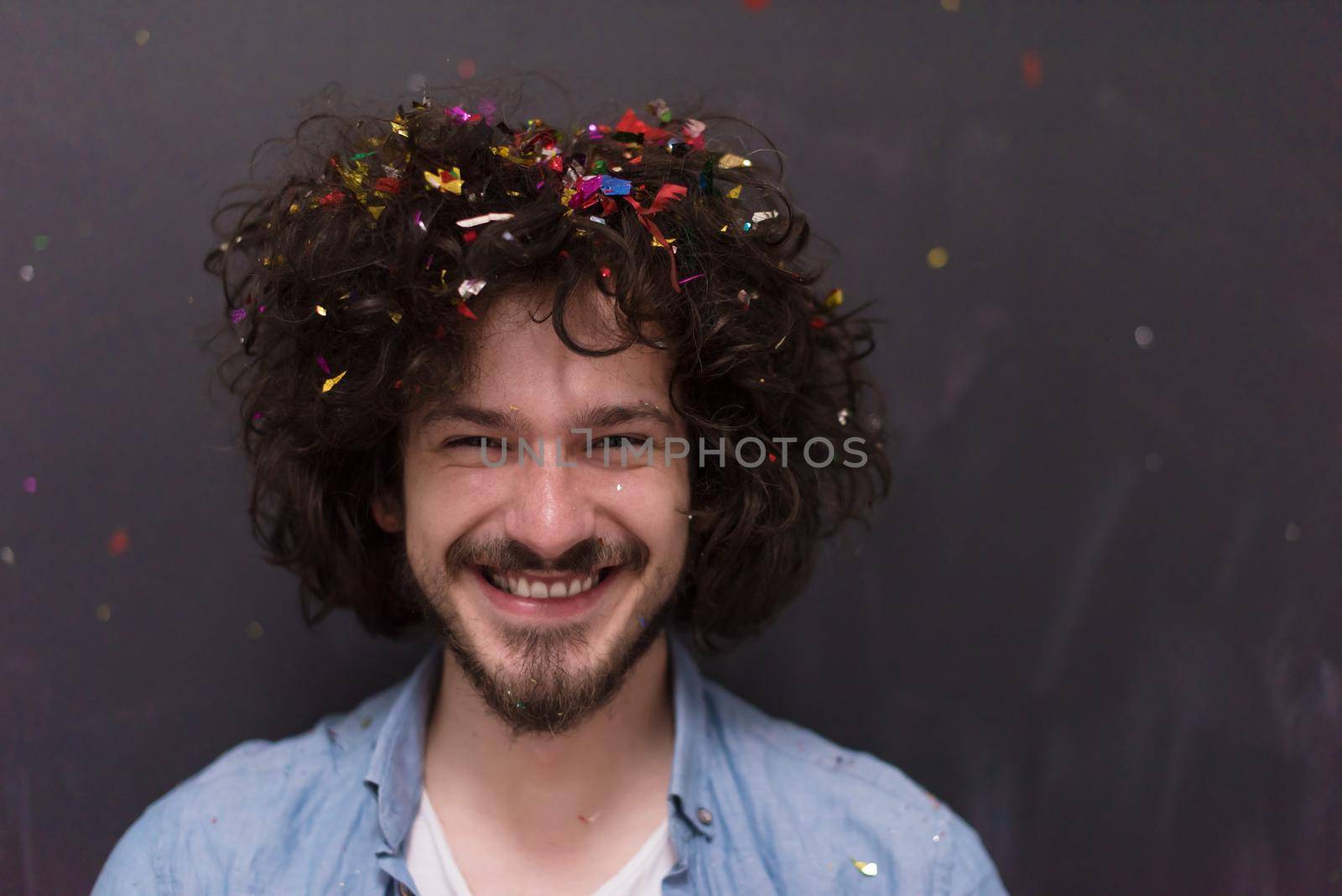 young man celebrating new year and chrismas party while blowing confetti decorations to camera