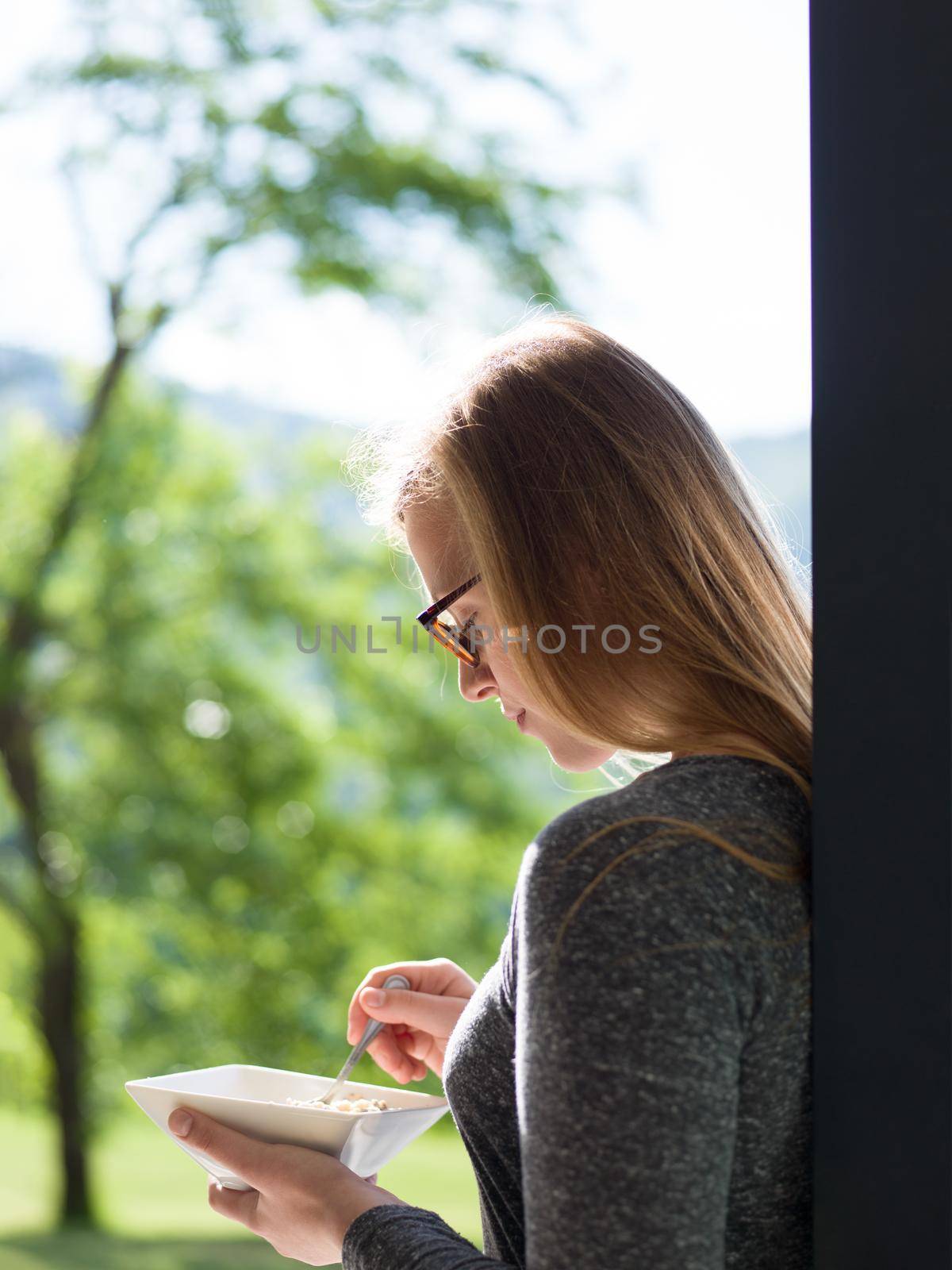 woman eating breakfast in front of her luxury home villa by dotshock