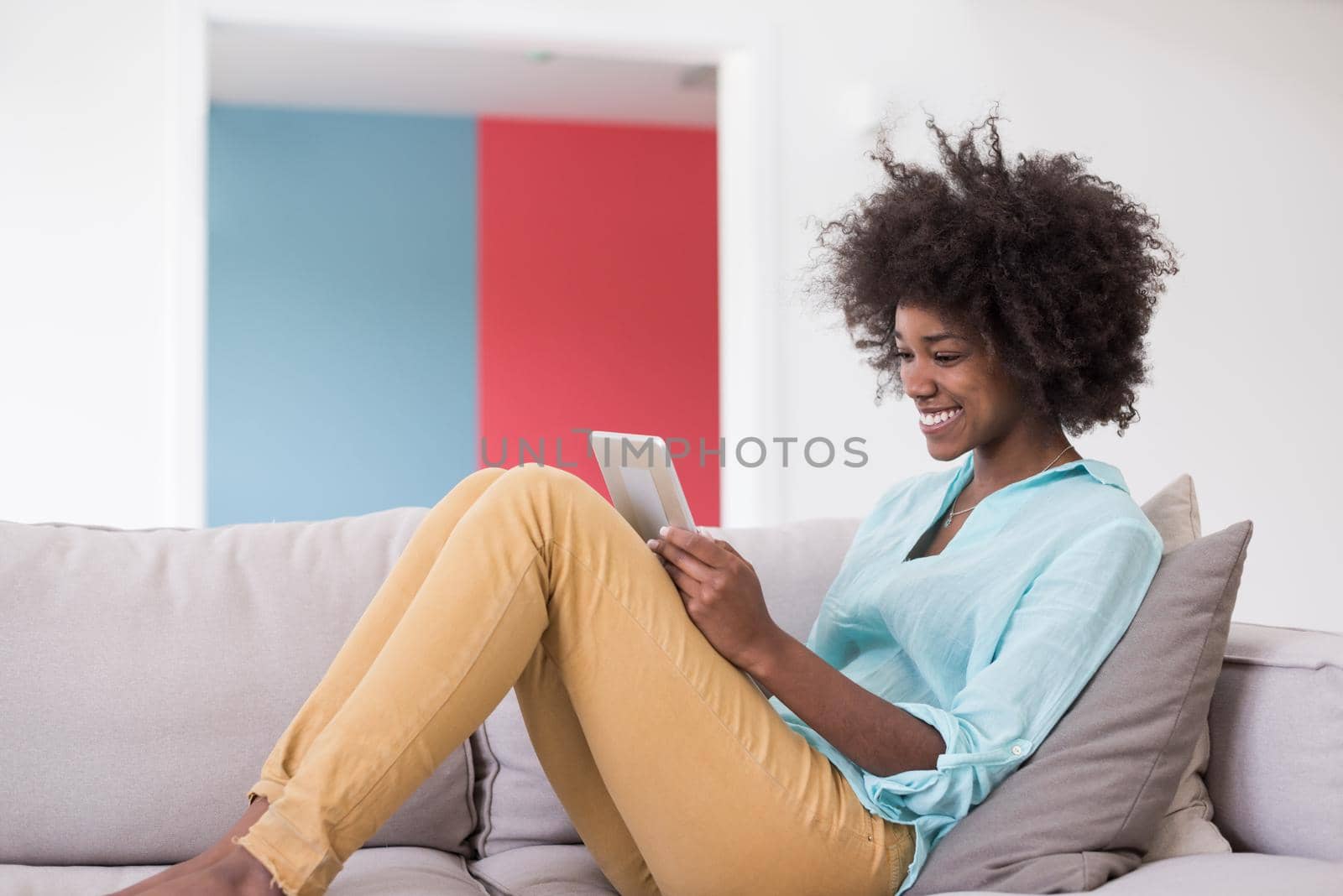 Young african american woman at home relaxing in her luxury lliving room reading a digital tablet PC surf internet and work