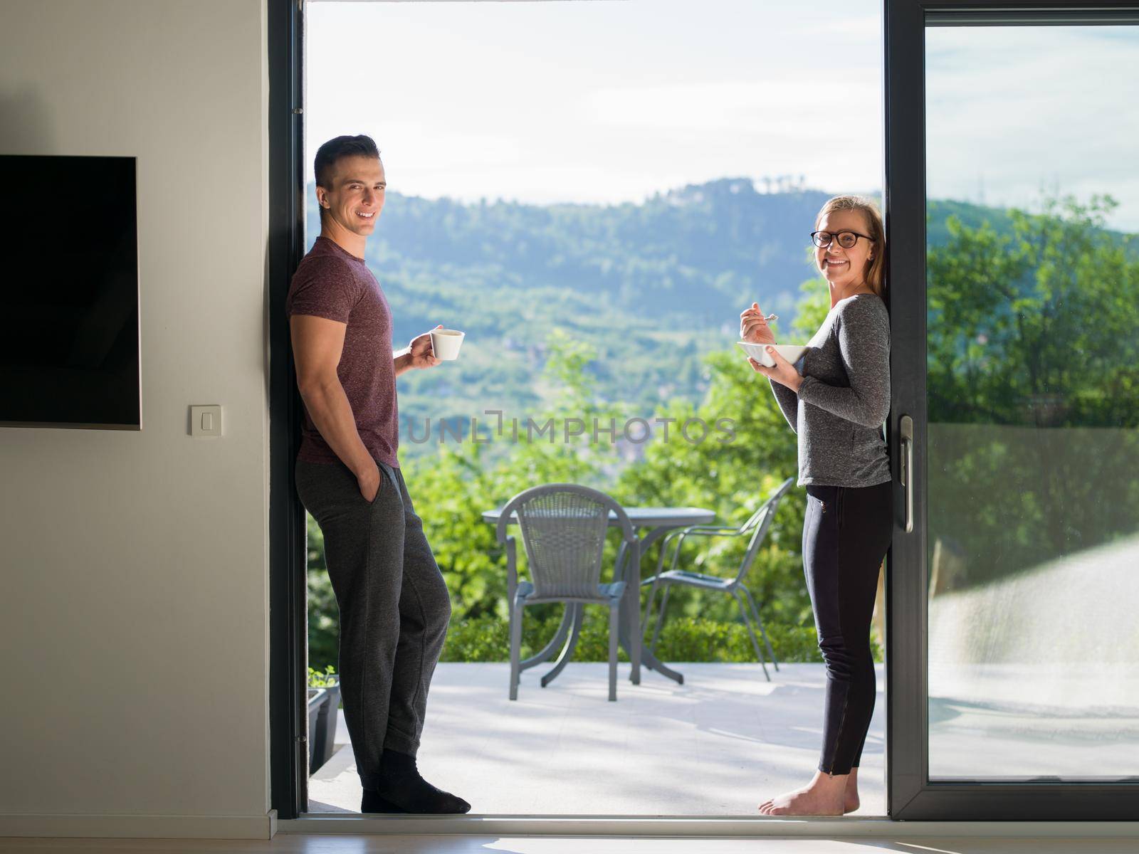 young beautiful handsome couple enjoying morning coffee and breakfast on the door of their luxury home villa