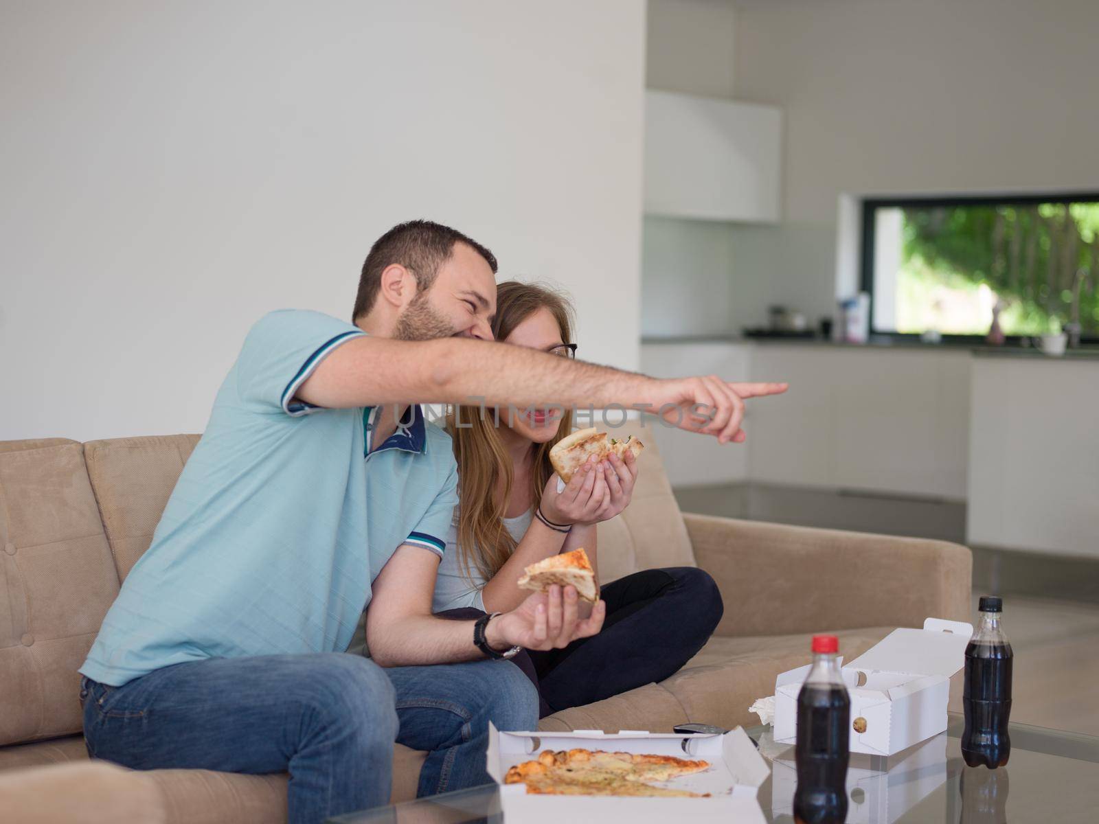 young handsome couple cheerfully spending time while eating pizza in their luxury home villa