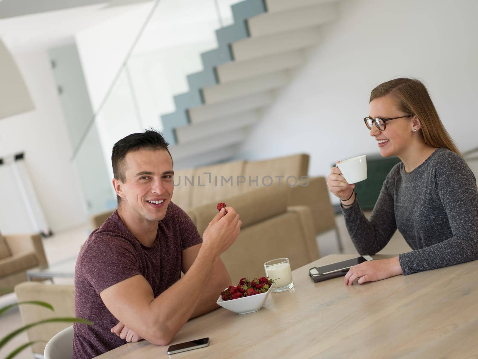 young beautiful handsome couple enjoying morning coffee and strawberries in their luxurious home villa