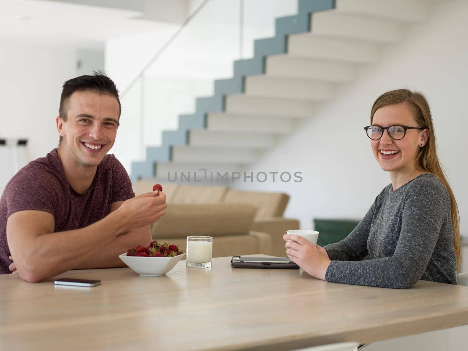 young beautiful handsome couple enjoying morning coffee and strawberries in their luxurious home villa