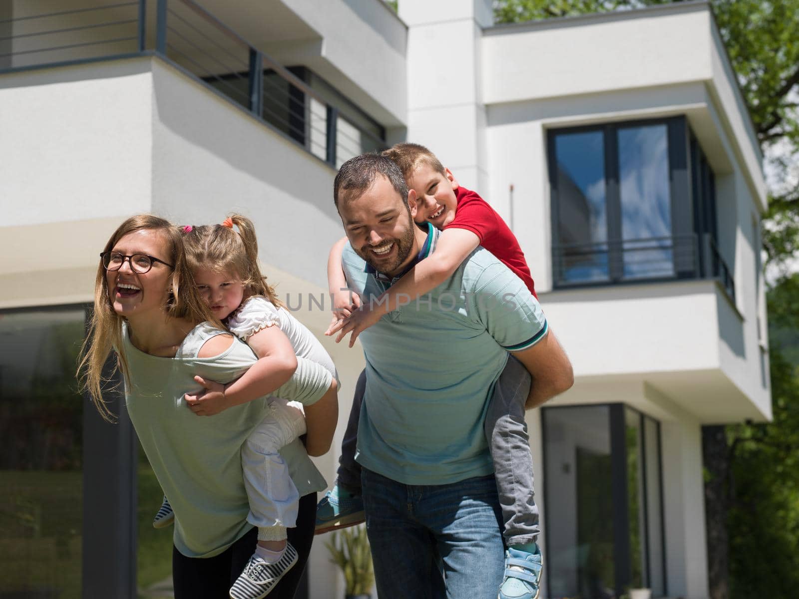 Portrait of young happy family with children in the yard in front of their luxury home of villa