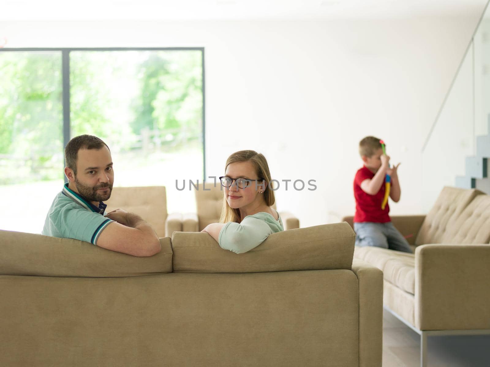 happy young family with little boy enjoys in the modern living room of their luxury home villa