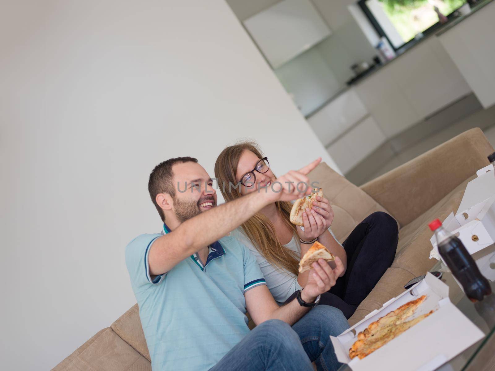 young handsome couple cheerfully spending time while eating pizza in their luxury home villa