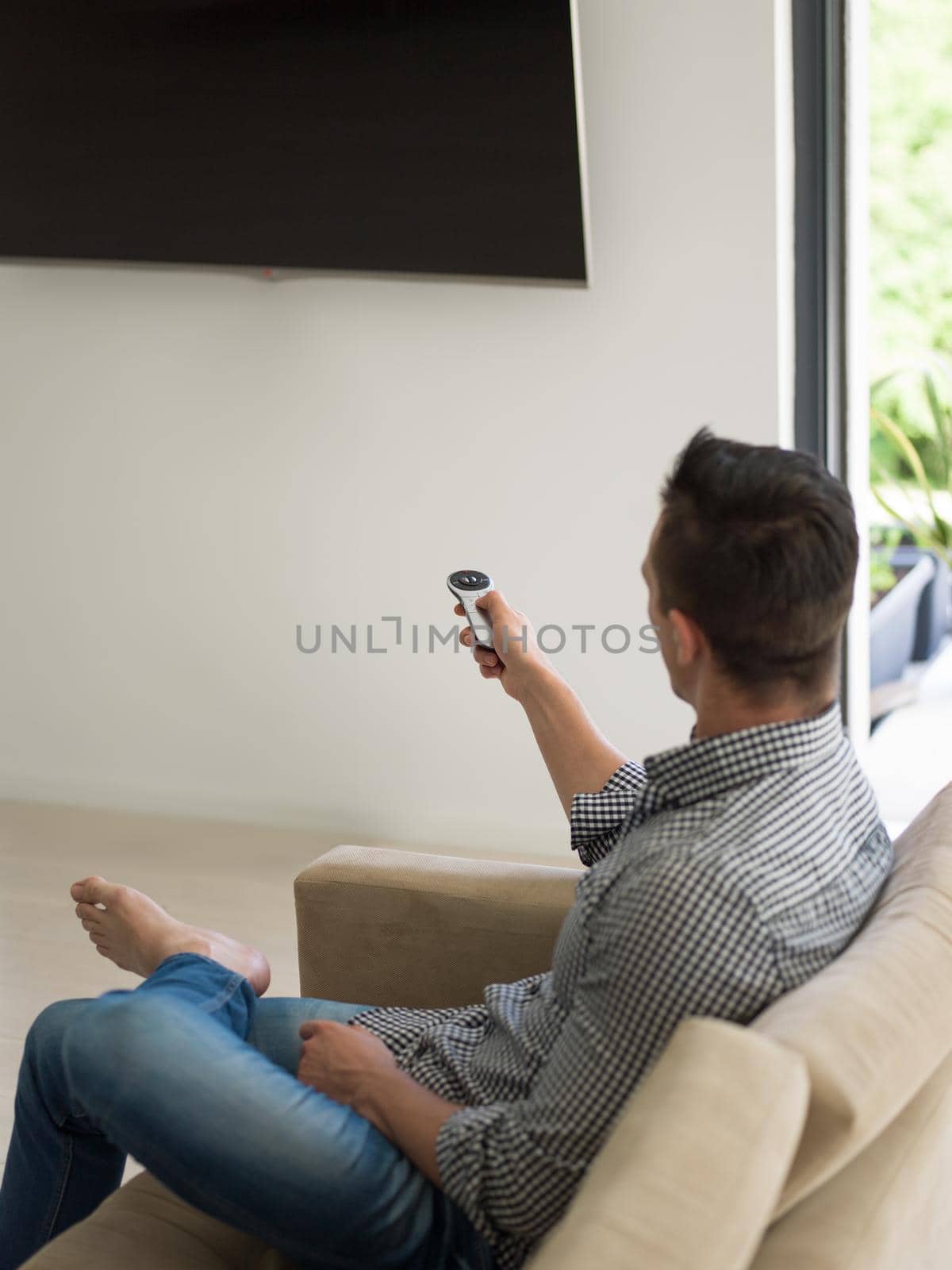 young handsome man enjoying free time watching television in his luxury home villa