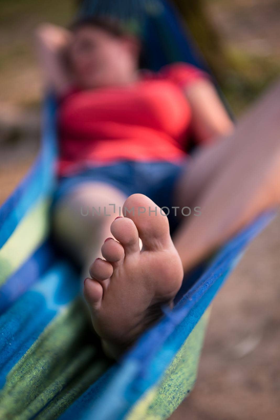 Young woman resting on hammock while enjoying nature on the river bank