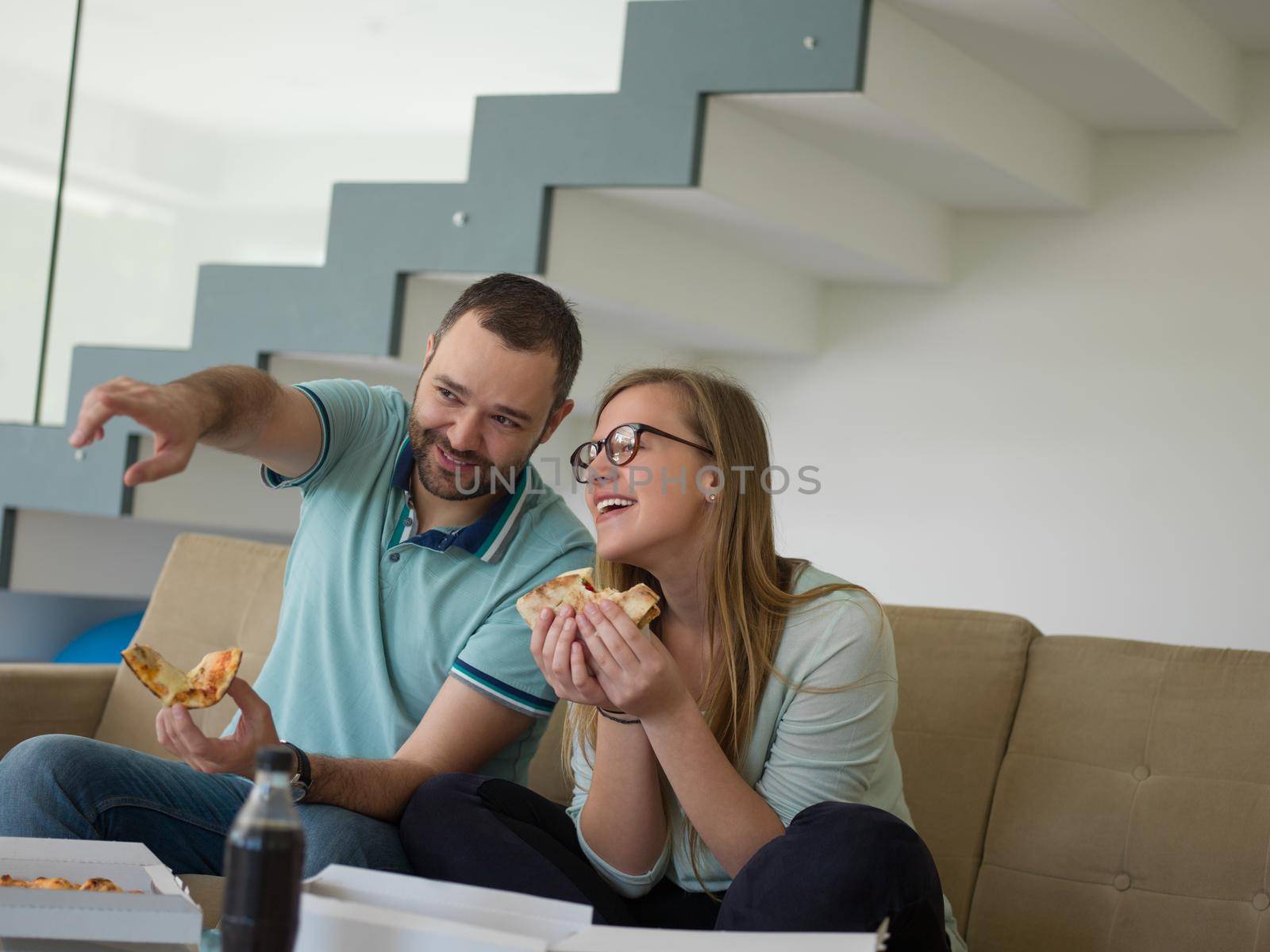 young handsome couple cheerfully spending time while eating pizza in their luxury home villa