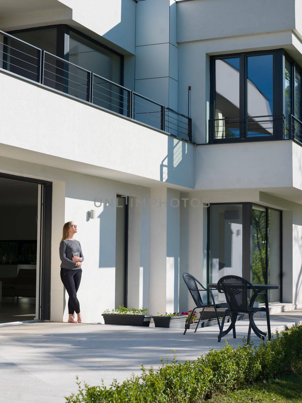 women using tablet computer in front of luxury home villa by dotshock