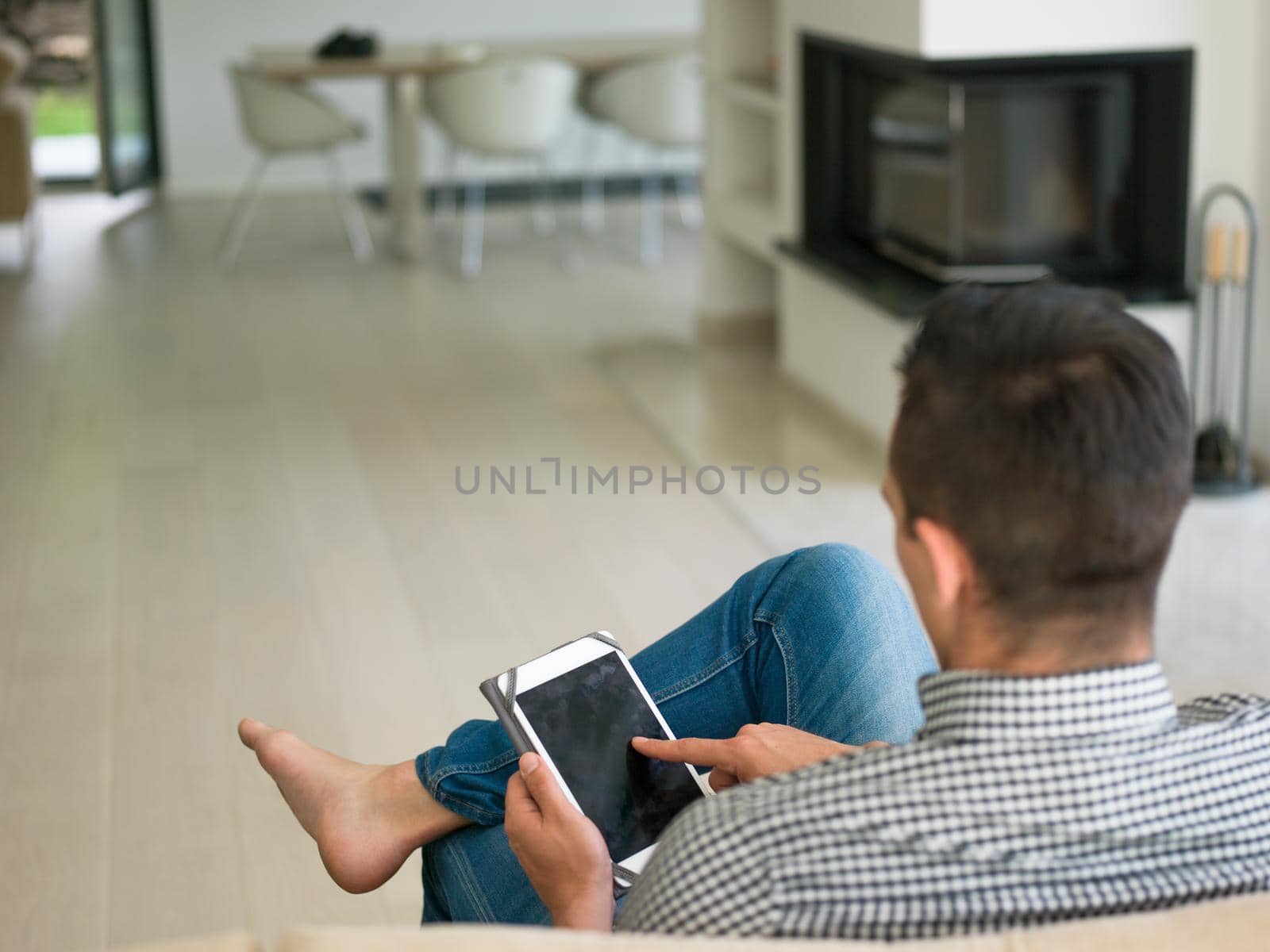 man on sofa using tablet computer by dotshock