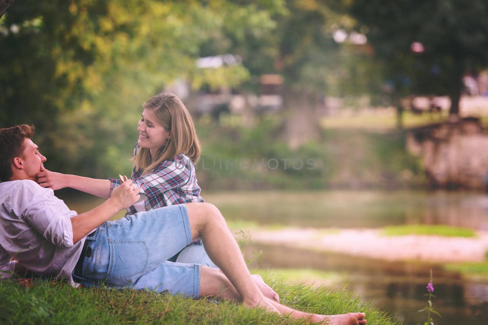 Couple in love enjoying picnic time drink and food in beautiful nature on the river bank