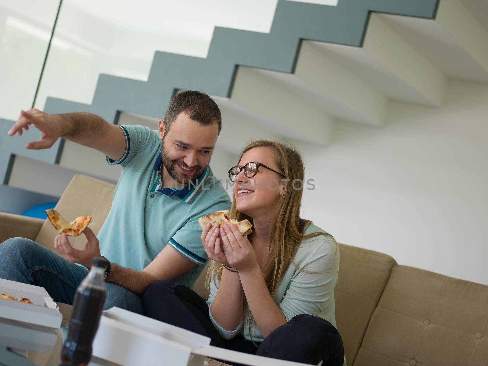 young handsome couple cheerfully spending time while eating pizza in their luxury home villa