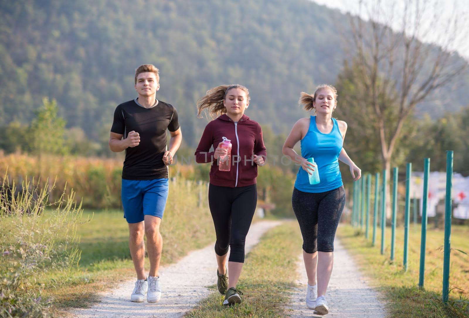 young people jogging on country road by dotshock