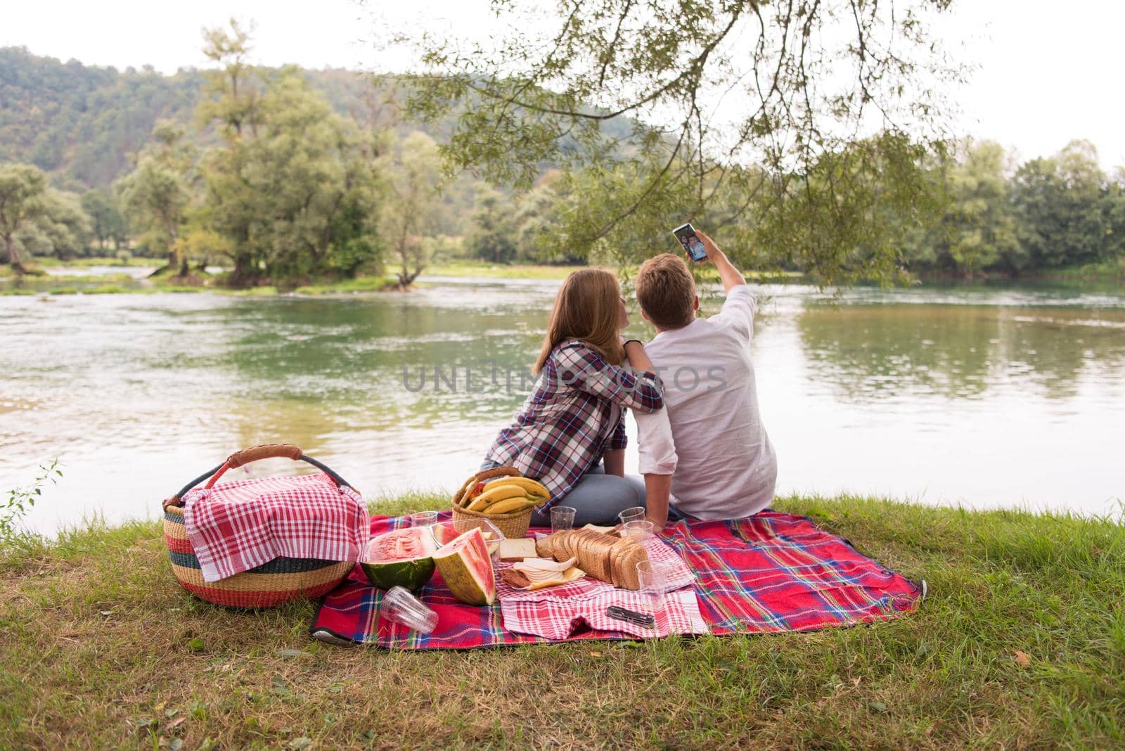 Couple taking a selfie by mobile phone while enjoying picnic time by dotshock