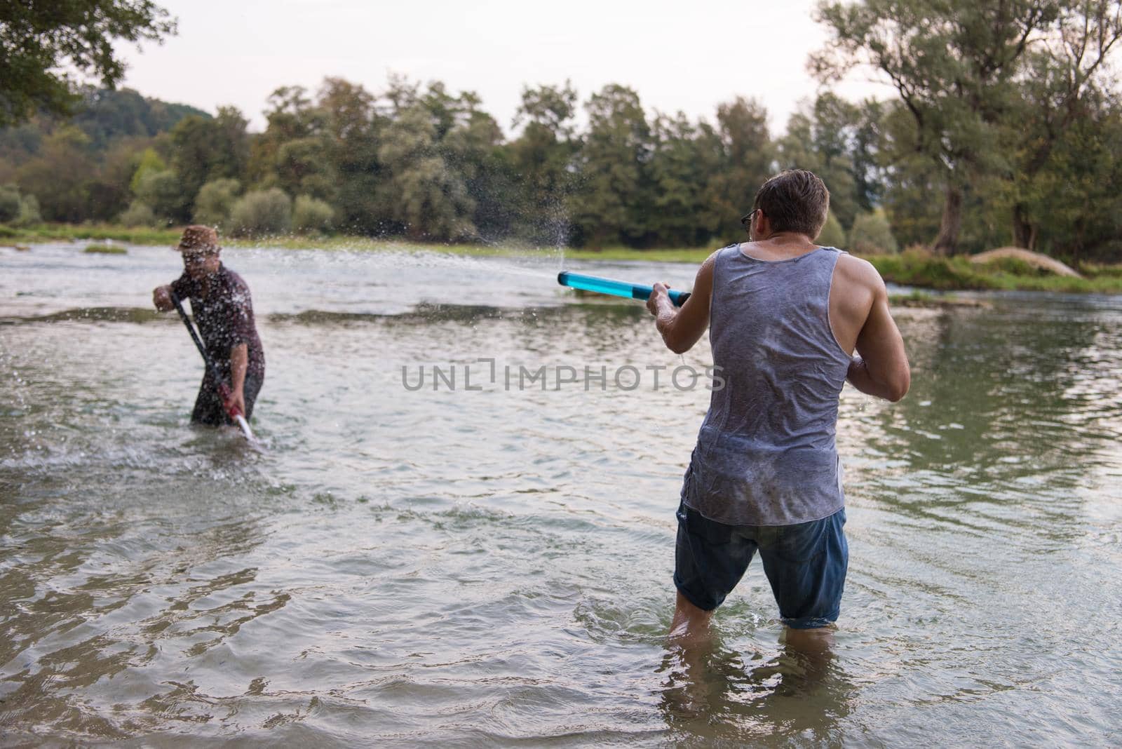 young men having fun with water guns by dotshock