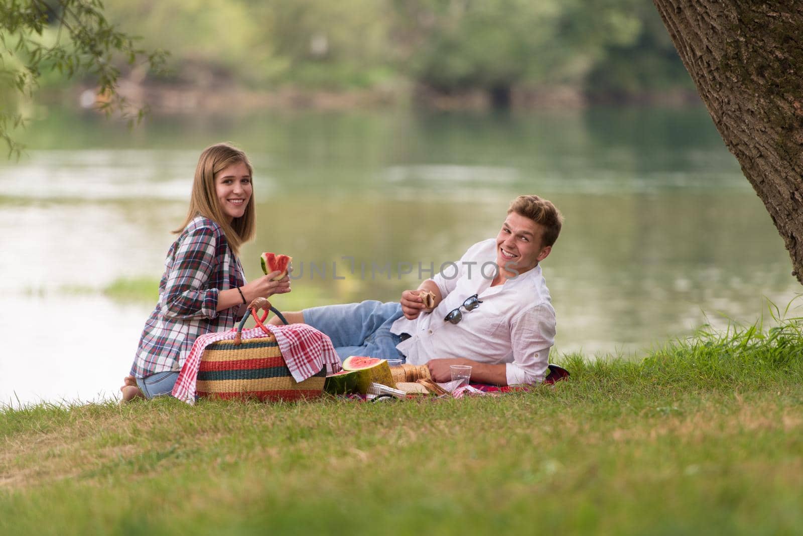 Couple in love enjoying picnic time drink and food in beautiful nature on the river bank