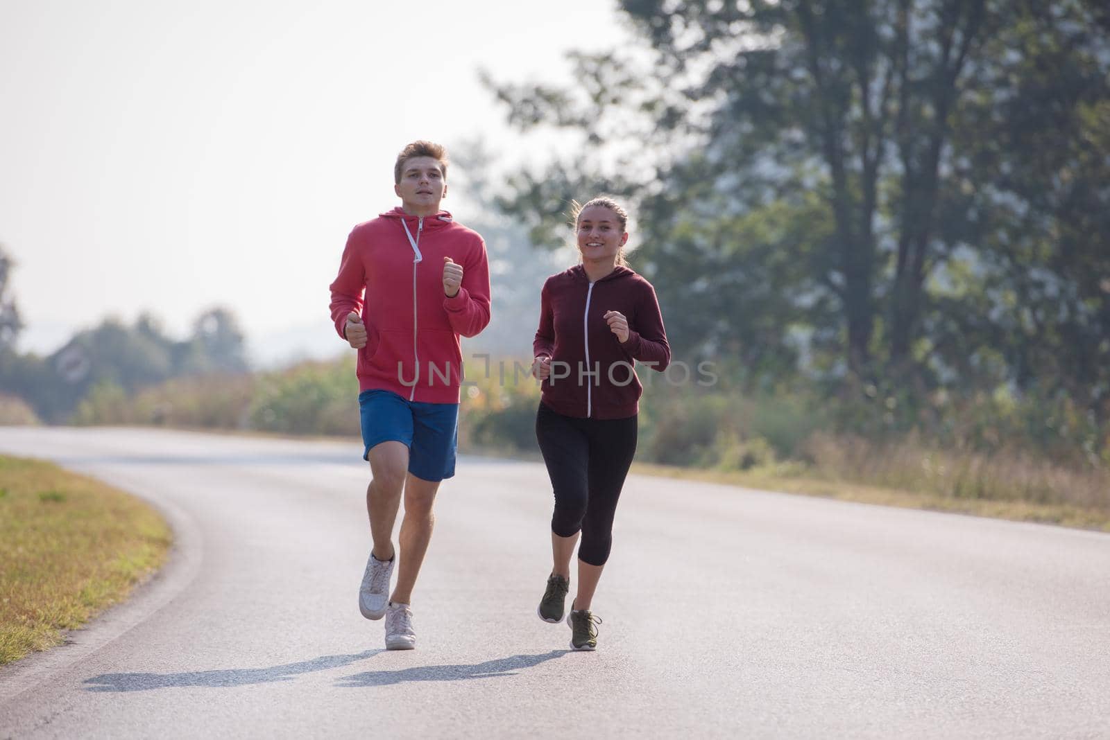 young couple enjoying in a healthy lifestyle while jogging along a country road, exercise and fitness concept