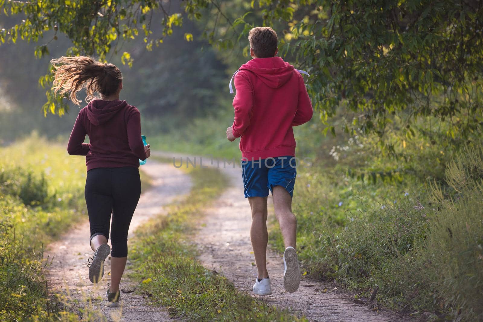 young couple enjoying in a healthy lifestyle while jogging along a country road, exercise and fitness concept