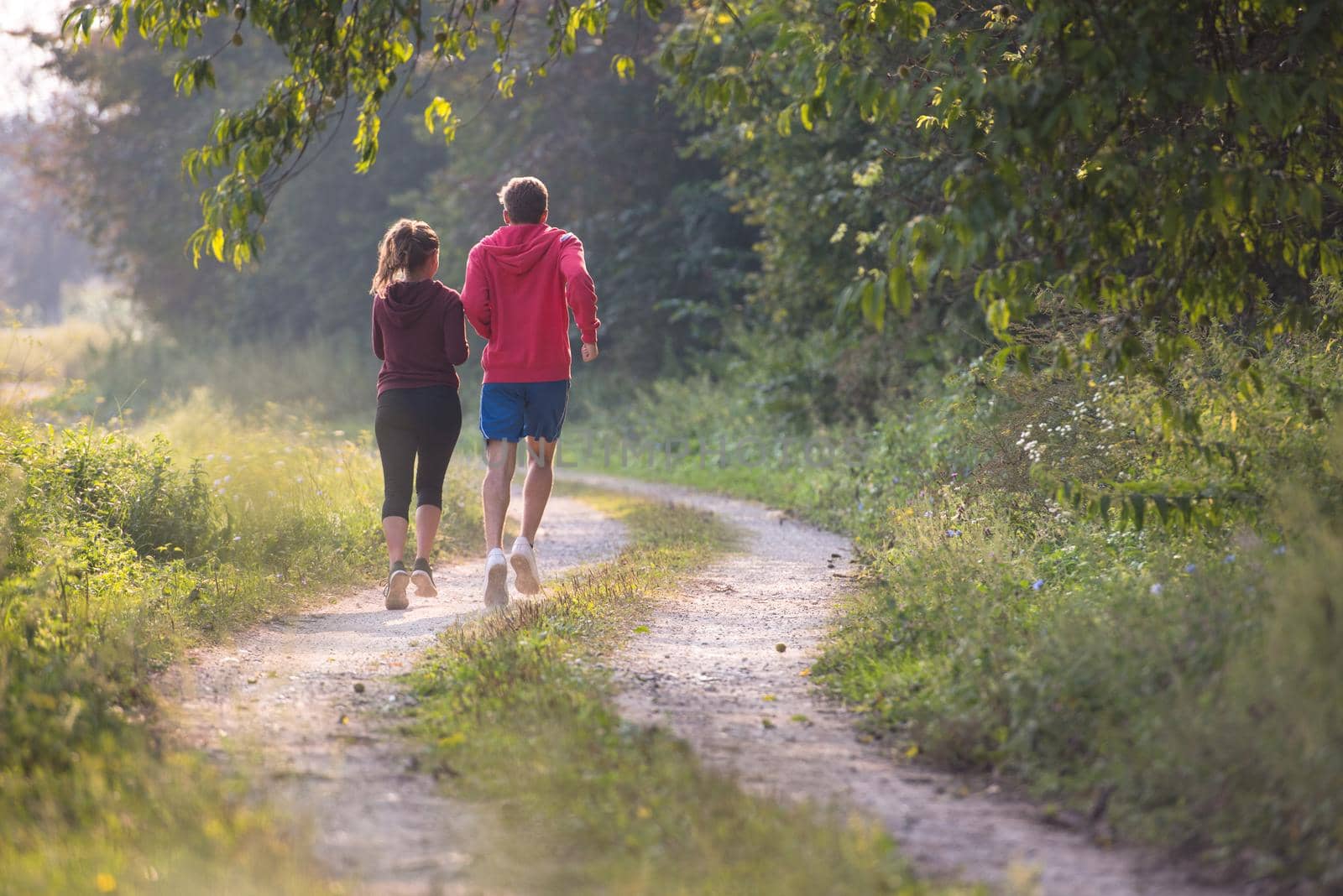 young couple jogging along a country road by dotshock