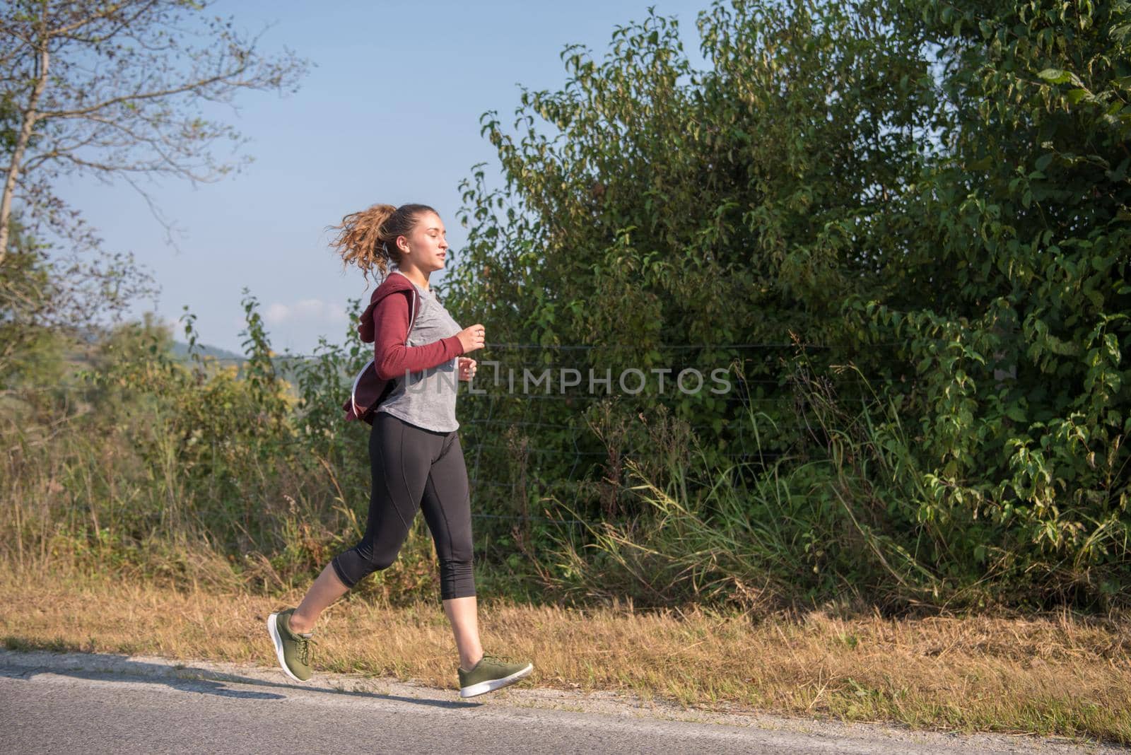 young woman enjoying in a healthy lifestyle while jogging along a country road, exercise and fitness concept