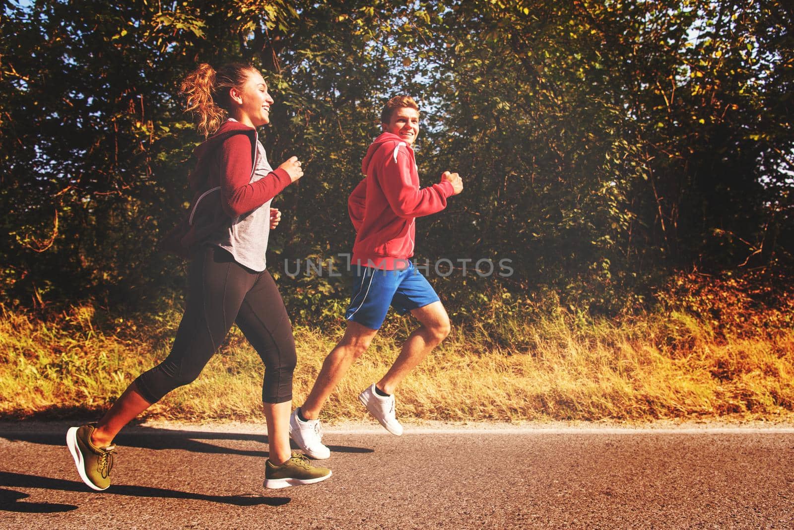 young couple enjoying in a healthy lifestyle while jogging along a country road, exercise and fitness concept