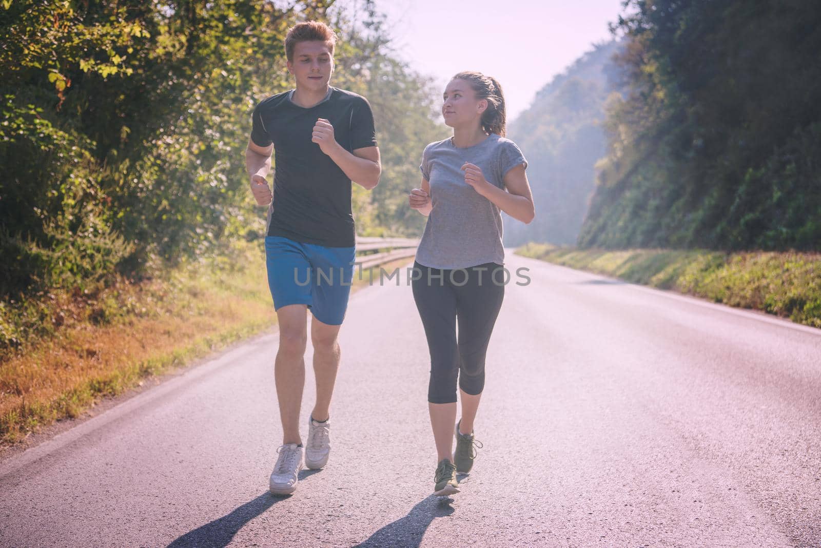 young couple enjoying in a healthy lifestyle while jogging along a country road, exercise and fitness concept