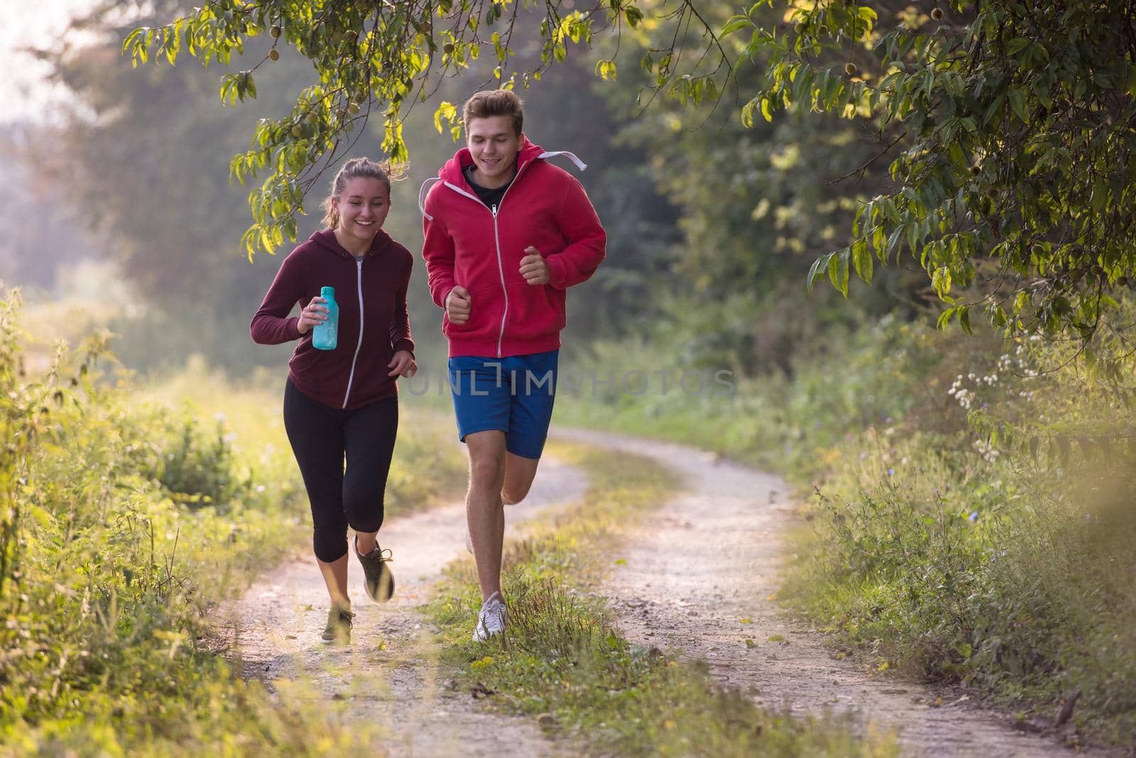 young couple enjoying in a healthy lifestyle while jogging along a country road, exercise and fitness concept