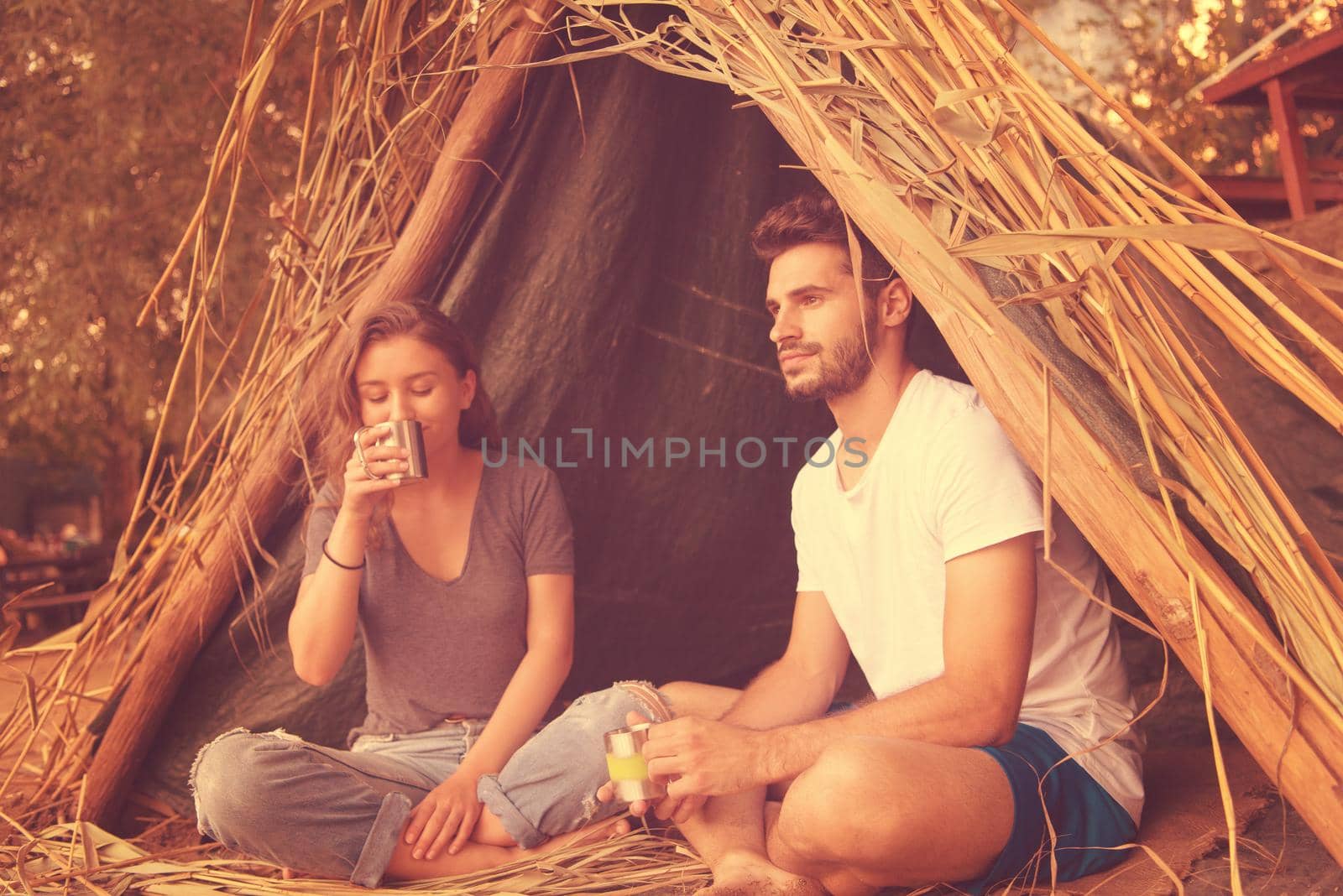 couple spending time together in straw tent by dotshock