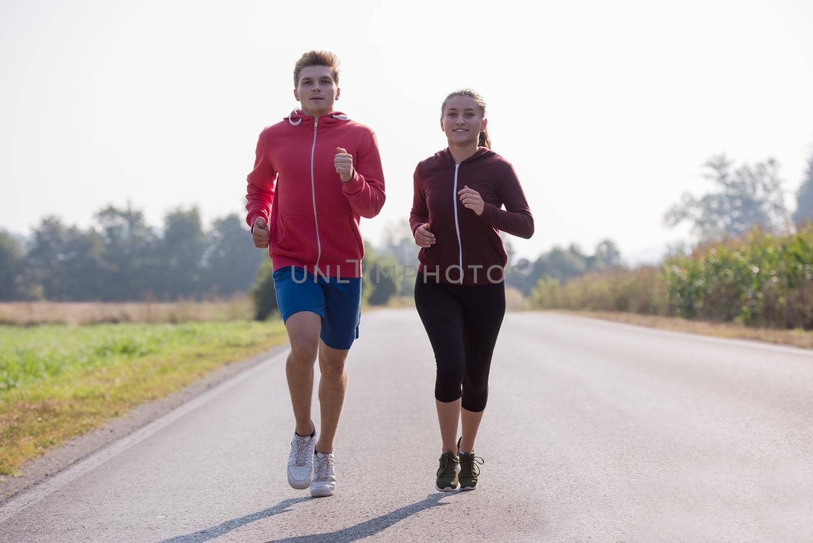 young couple enjoying in a healthy lifestyle while jogging along a country road, exercise and fitness concept