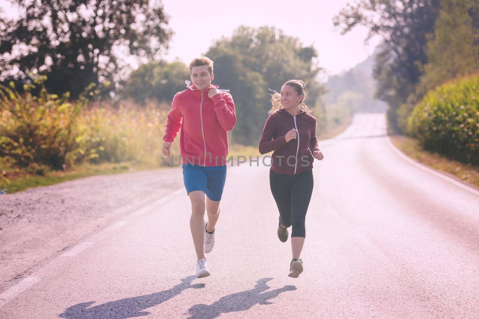 young couple enjoying in a healthy lifestyle while jogging along a country road, exercise and fitness concept