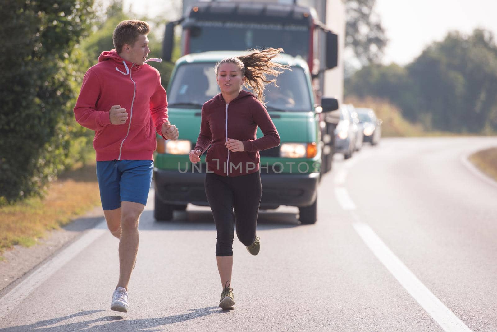 young couple enjoying in a healthy lifestyle while jogging along a country road, exercise and fitness concept