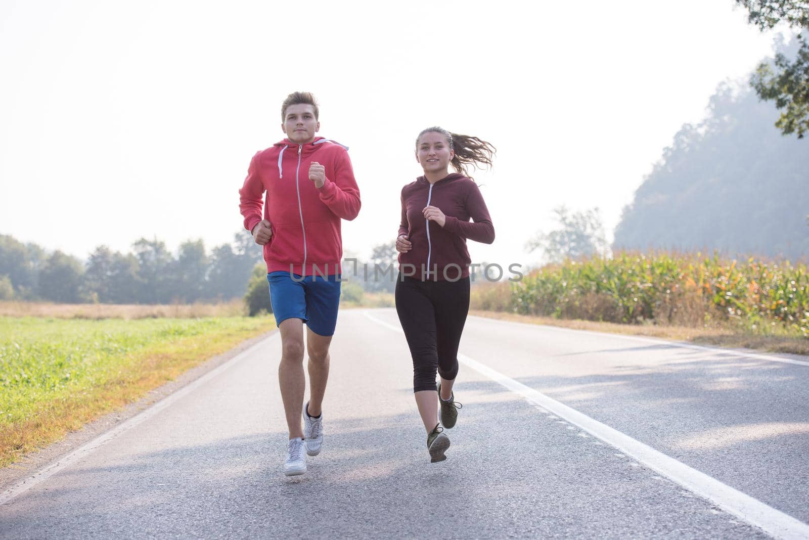 young couple jogging along a country road by dotshock