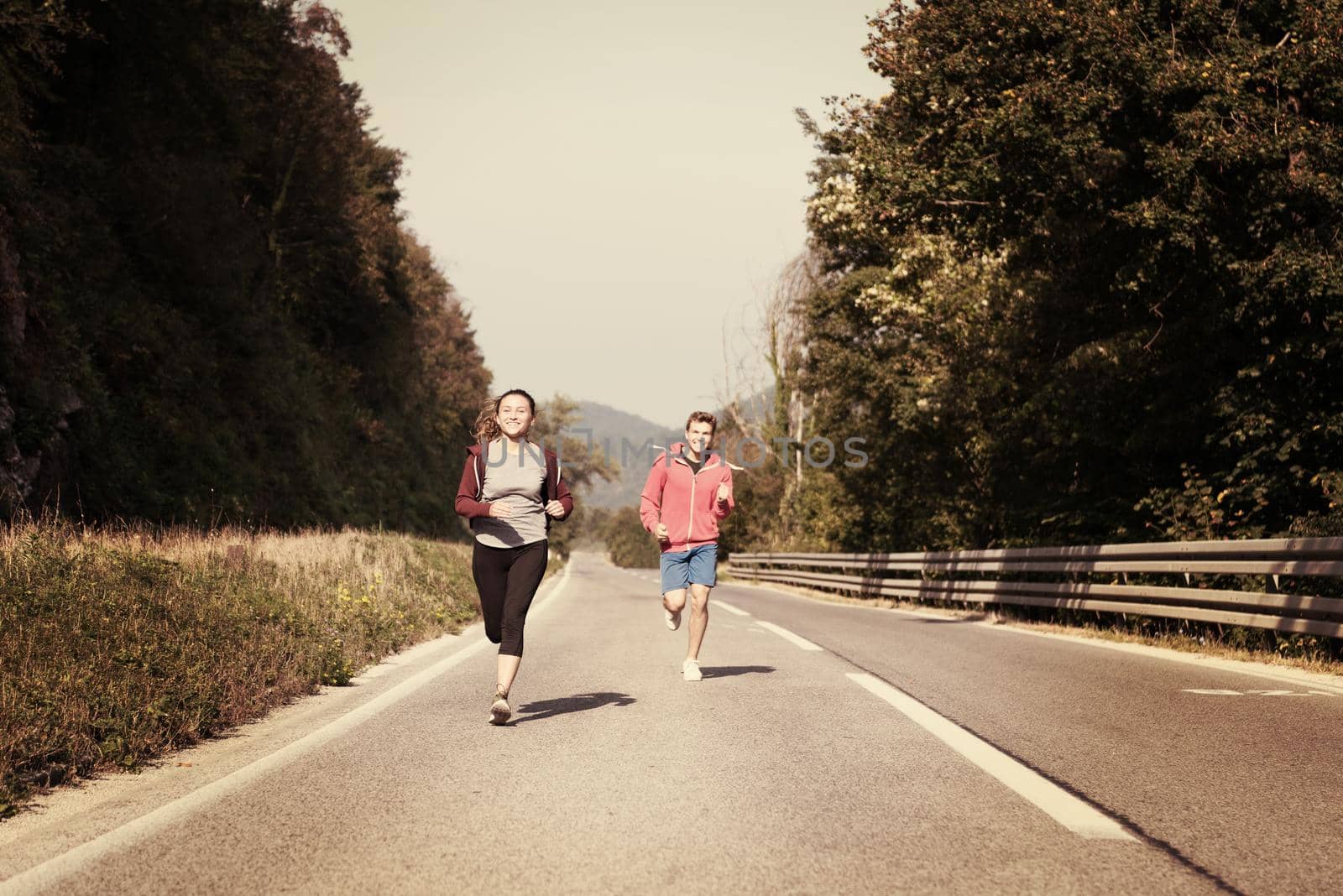 young couple jogging along a country road by dotshock