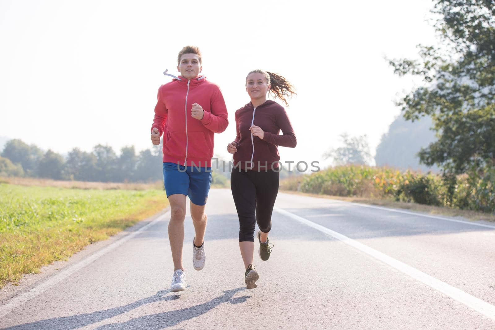 young couple jogging along a country road by dotshock
