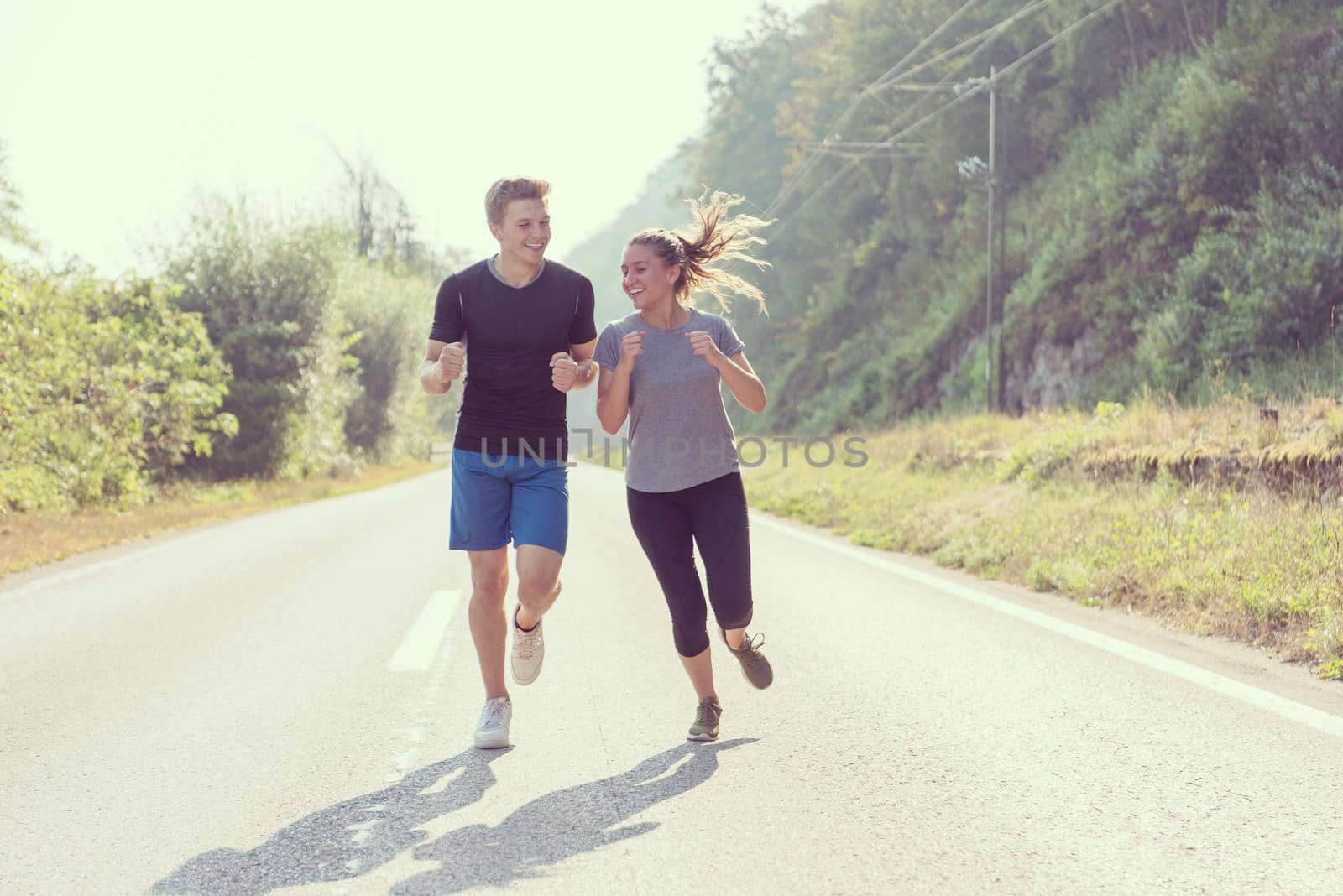 young couple enjoying in a healthy lifestyle while jogging along a country road, exercise and fitness concept