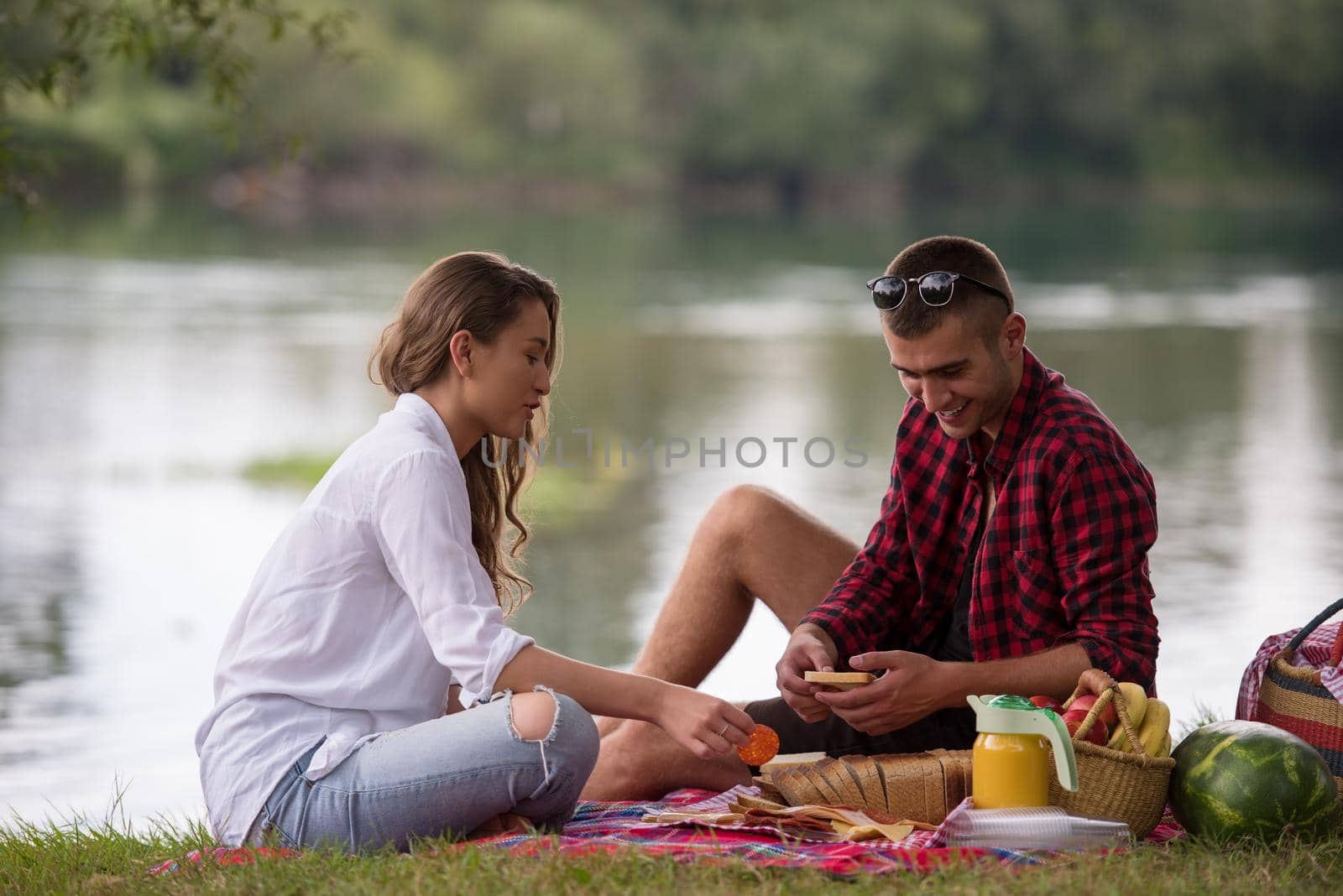 Couple in love enjoying picnic time drink and food in beautiful nature on the river bank