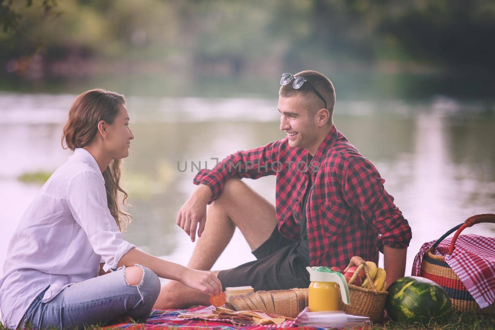 Couple in love enjoying picnic time drink and food in beautiful nature on the river bank