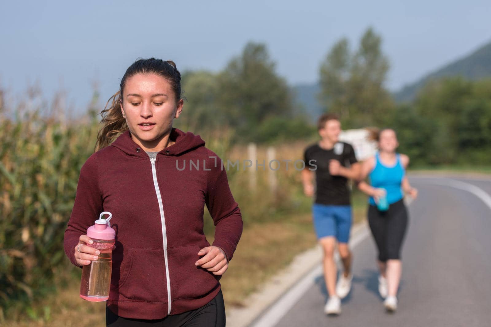 group of young people jogging on country road runners running on open road on a summer day