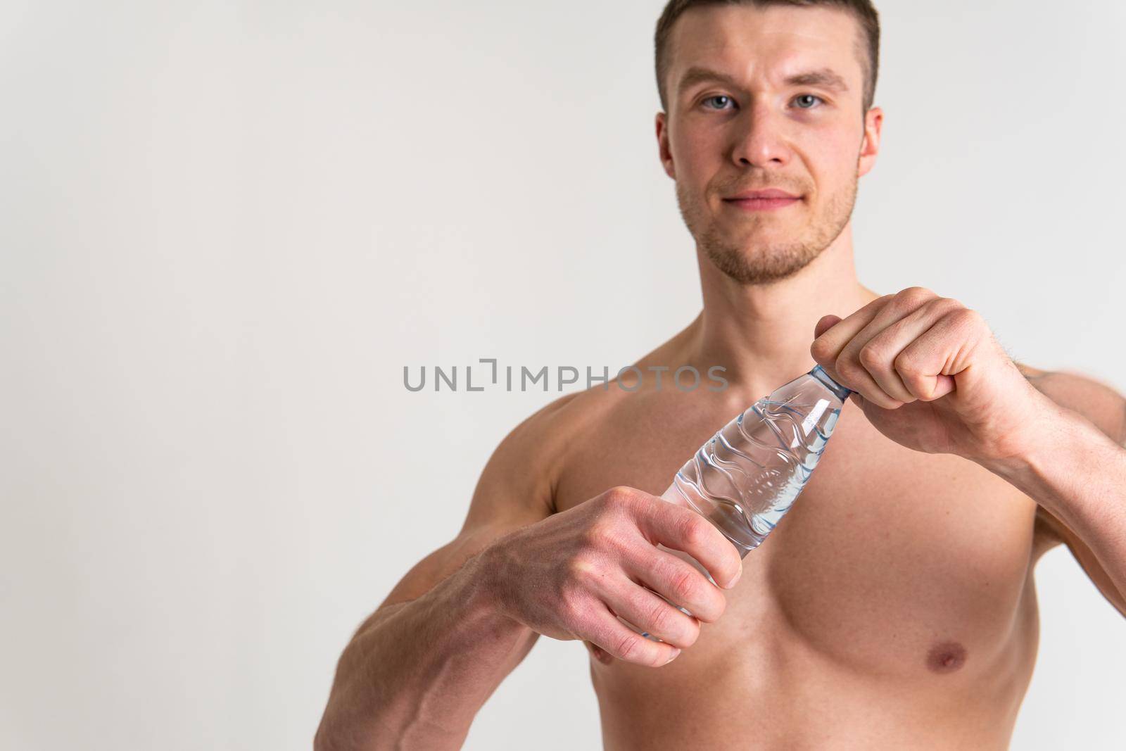 Male drink-water fitness is pumped with a towel on a white background isolated muscular body, healthy energy bottle holding, hydration. Bodybuilding copy powerful one muscle by 89167702191